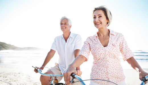 Senior couple riding bikes on a beach
